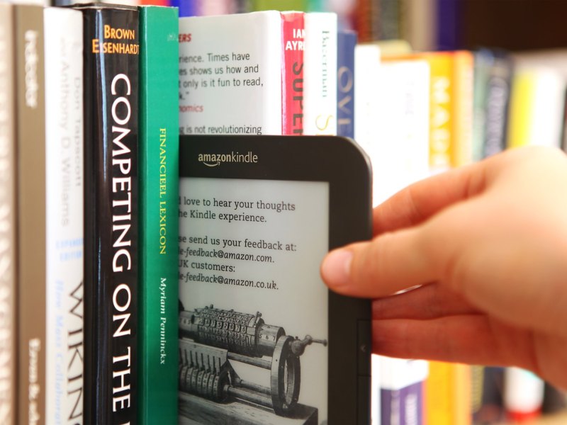 eBook-Reader Kindle von Amazon wird aus Bücherregal gezogen