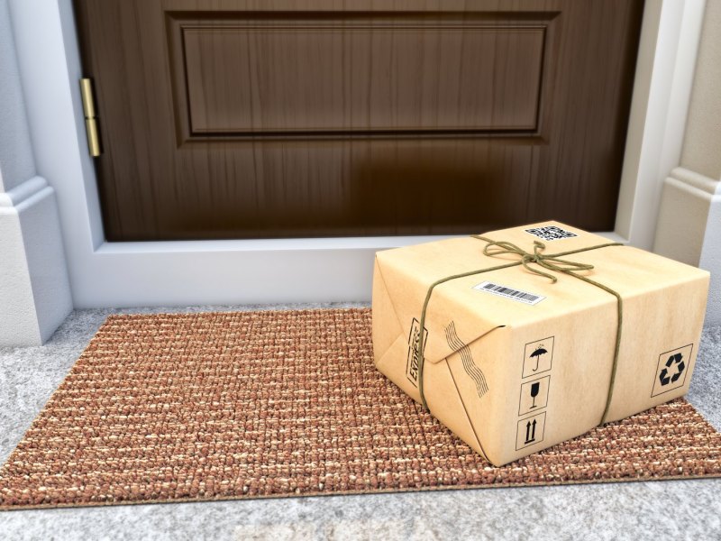Ein Paket liegt auf dem Boden vor der Haustür.