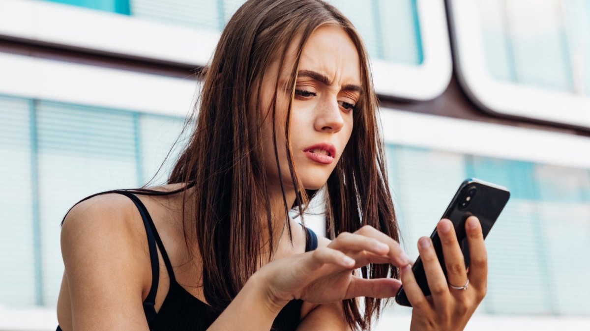 Frau blickt besorgt auf ihr Handy.