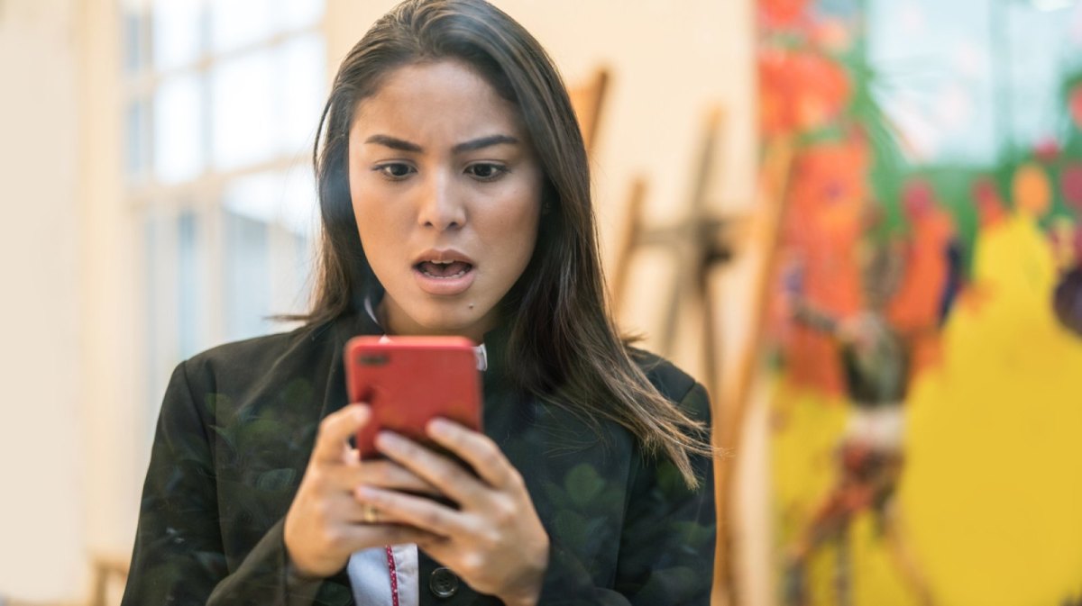 Frau sieht schockiert auf ihr Handy.