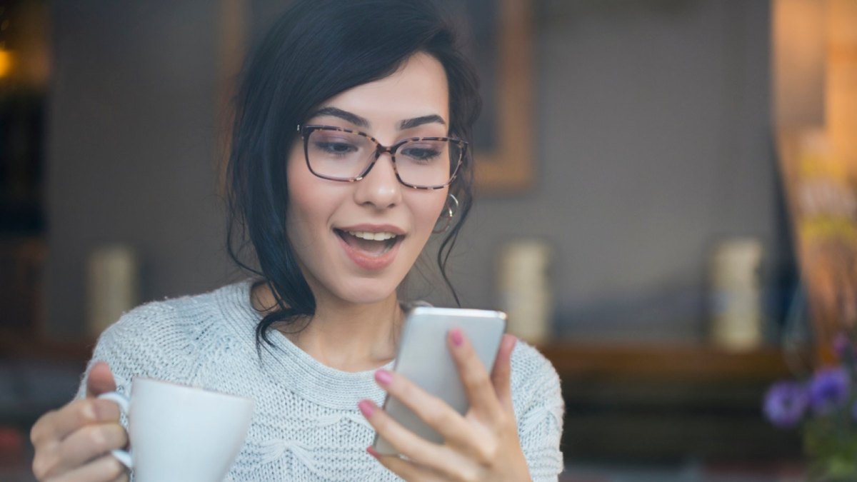 Frau blickt überrascht auf ihr Handy.