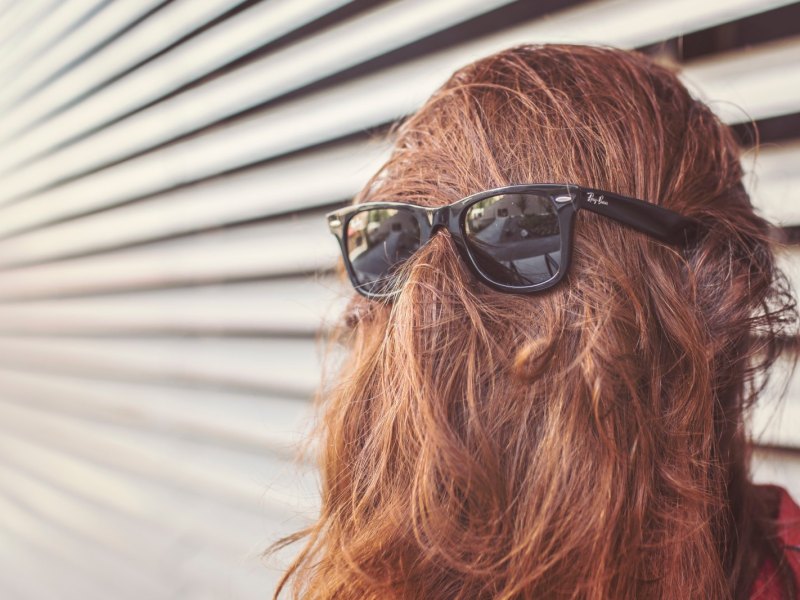 Frau mit Haaren im Gesicht und Sonnenbrille