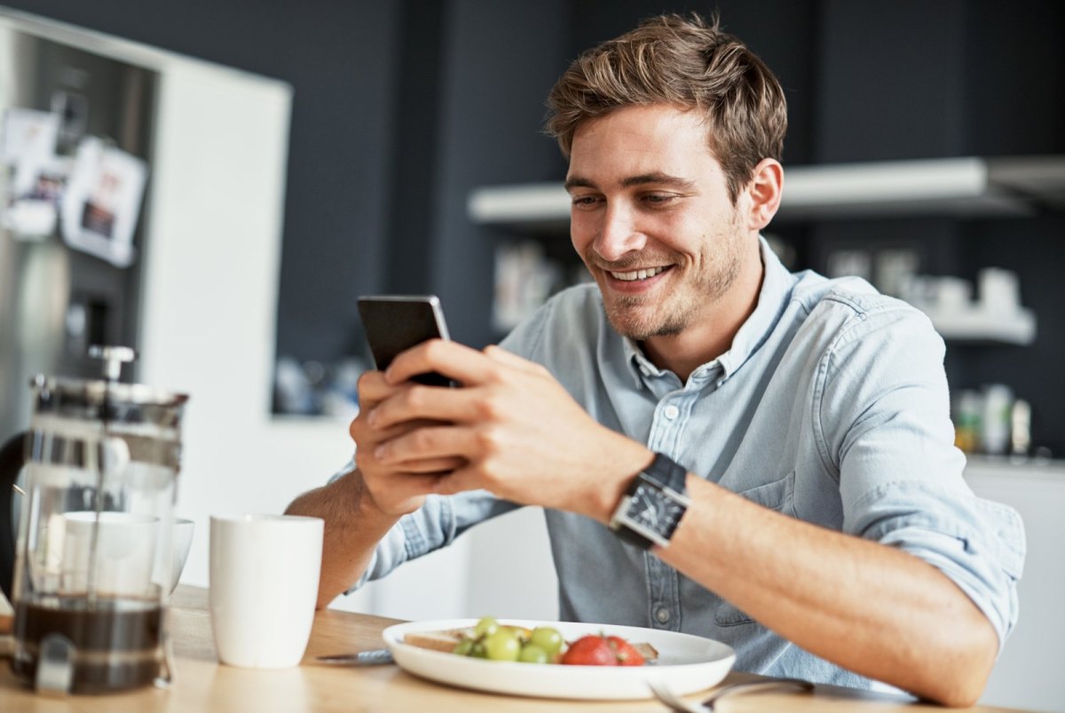 Mann blickt glücklich aufs Handy.