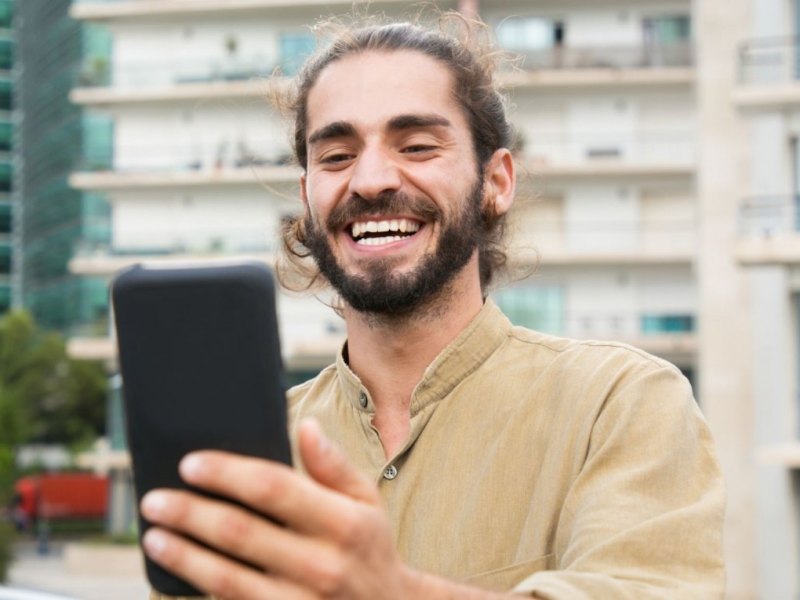 Mann schaut glücklich aufs Handy