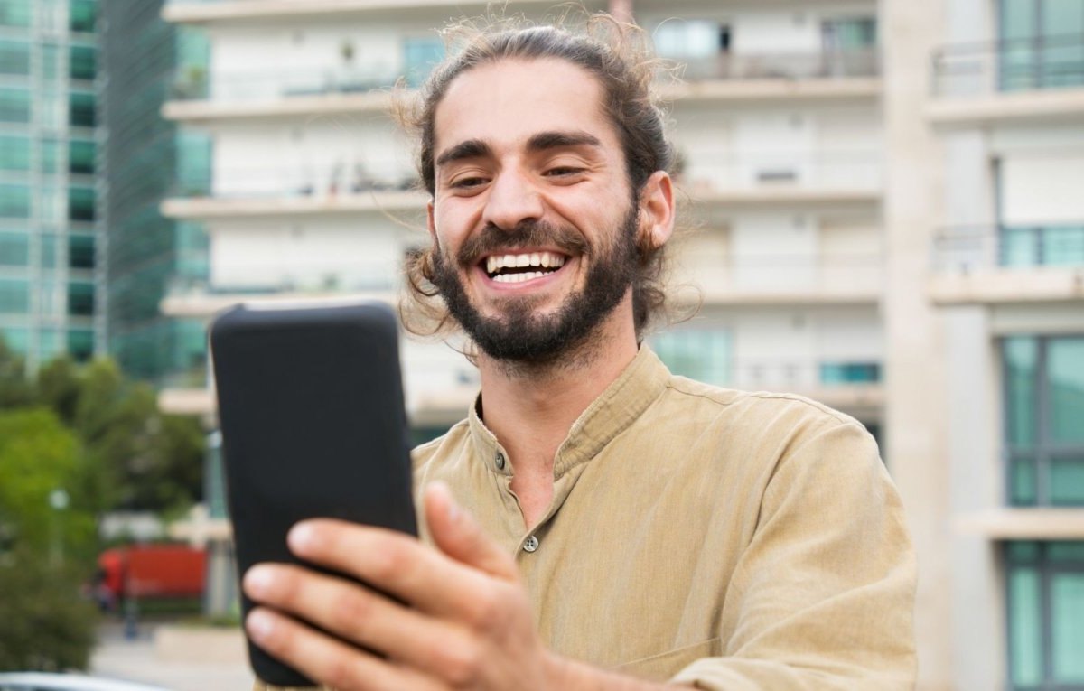 Mann schaut glücklich aufs Handy