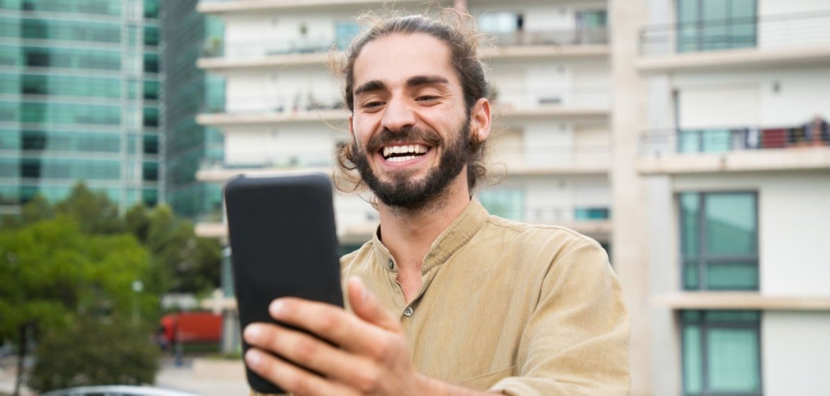 Mann schaut glücklich aufs Handy