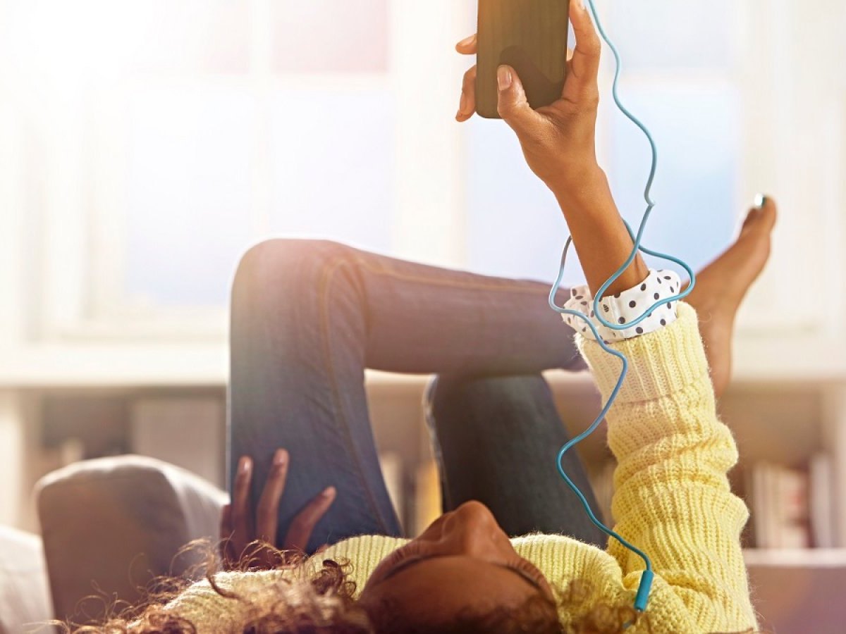 Frau hört Musik mit Kopfhörern an ihrem Handy.