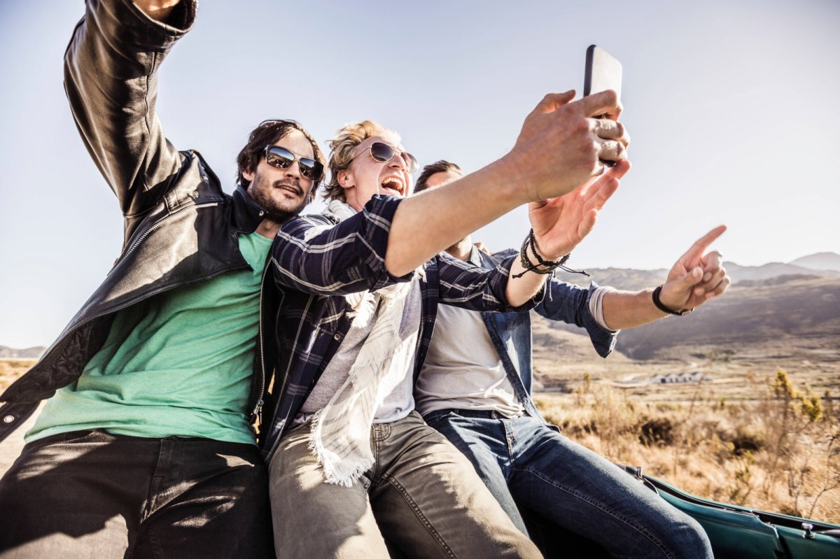 Drei Freunde sind unterwegs und filmen sich mit dem Handy.