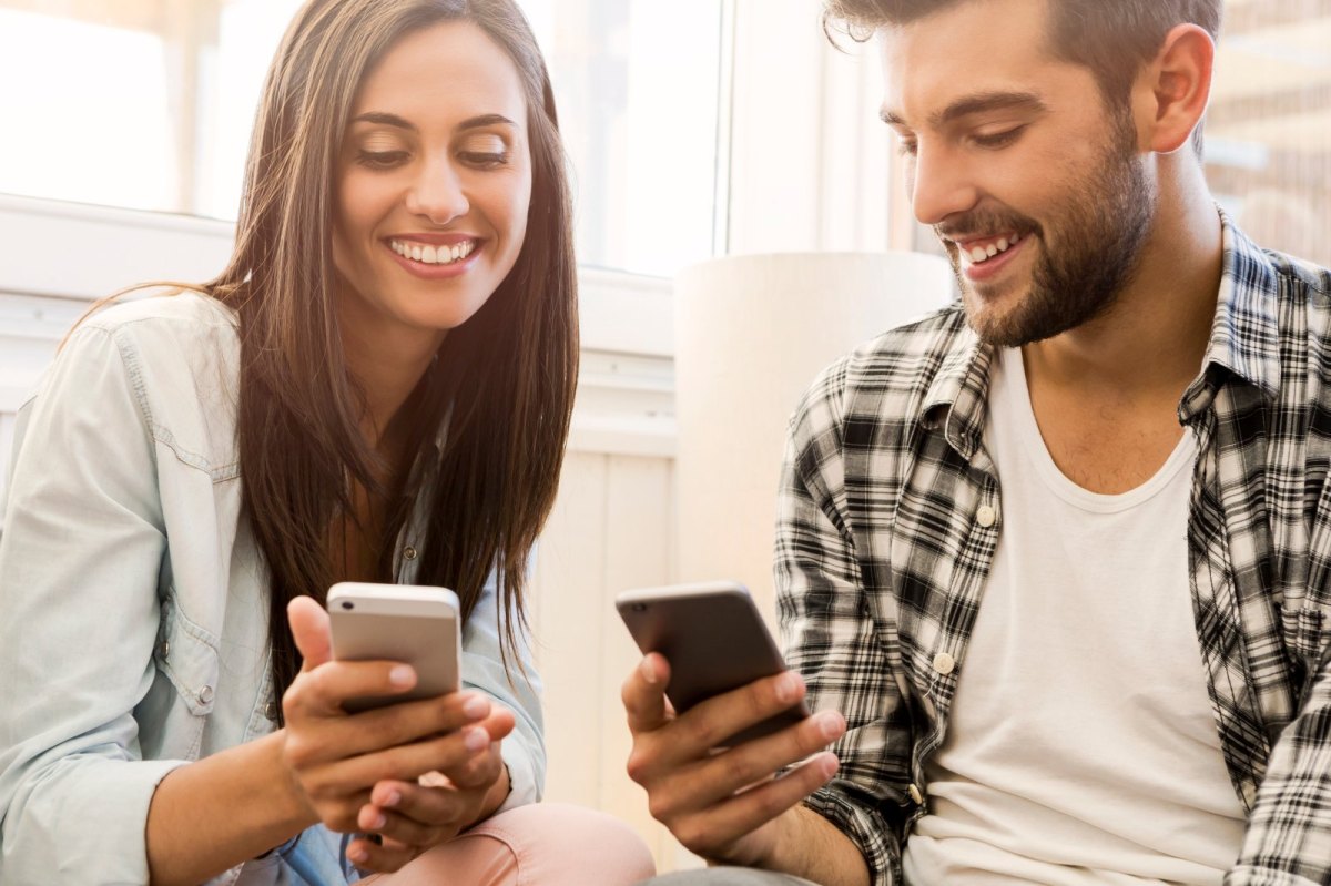 Ein Mann und eine Frau schauen glücklich auf ihr Handy