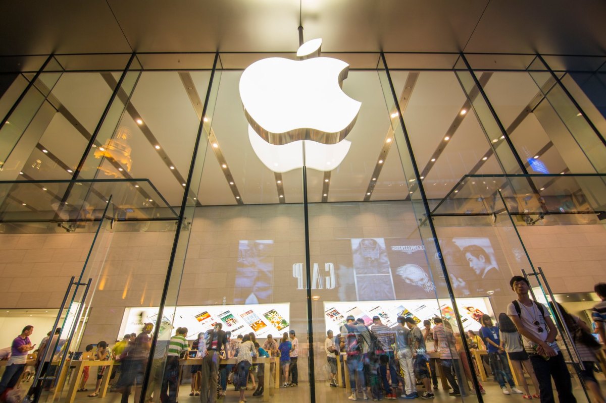 Apple-Store von vorne mit dem berühmten abgebissenen Apfel als Logo und Besuchern in Hintergrund.