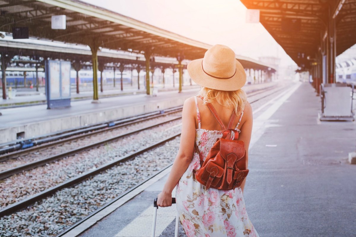 Frau am Bahnhof mit Koffer