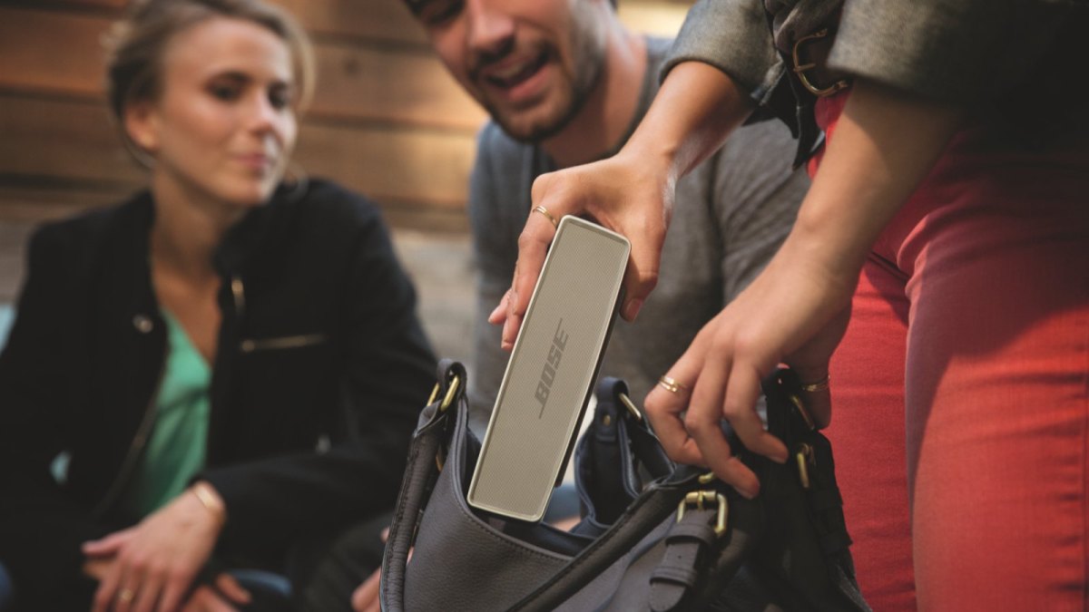 Eine Frau holt eine portable Bose-Box aus ihrer Tasche.