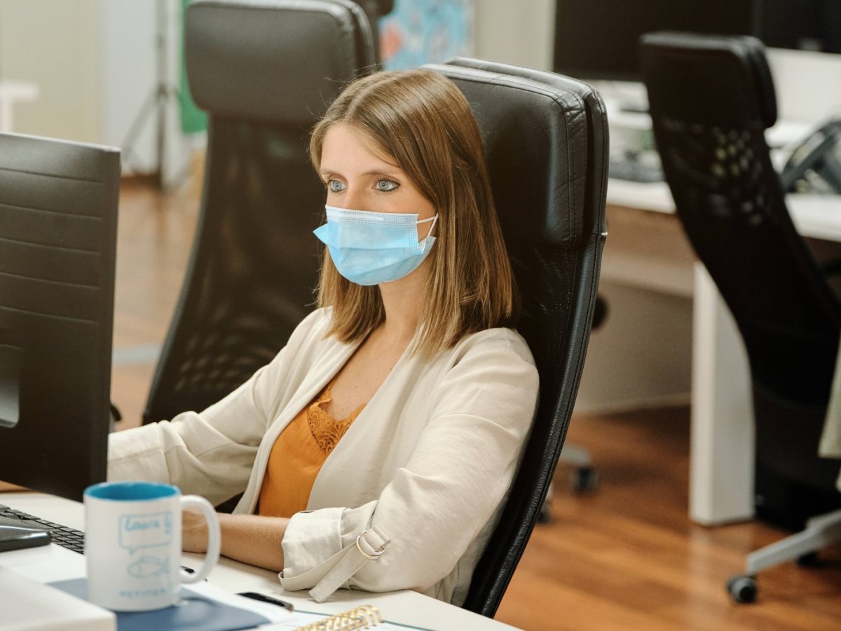 Frau am Arbeitsplatz mit Corona maske