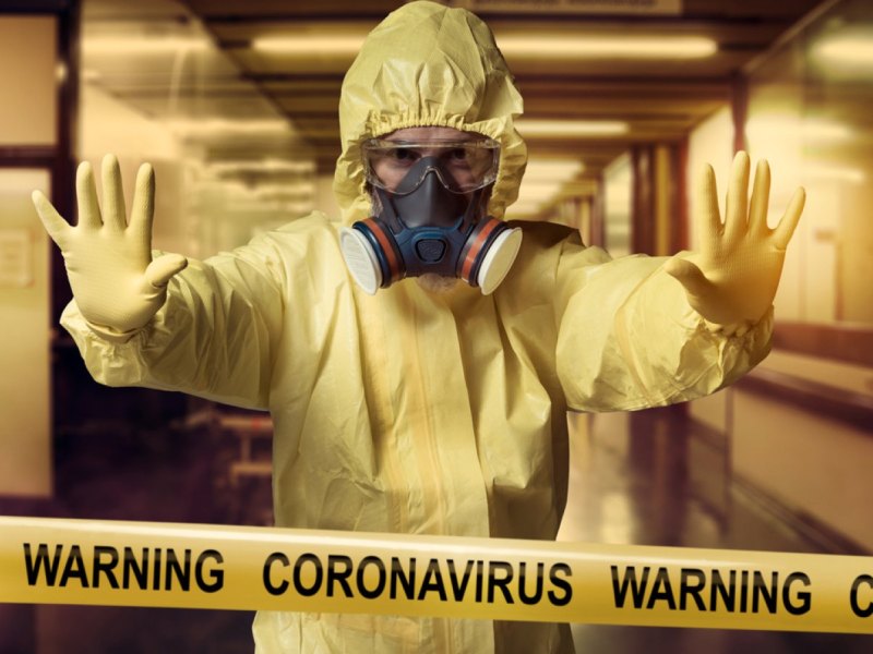 Coronavirus-Warnkordonband und Mann im Schutzanzug