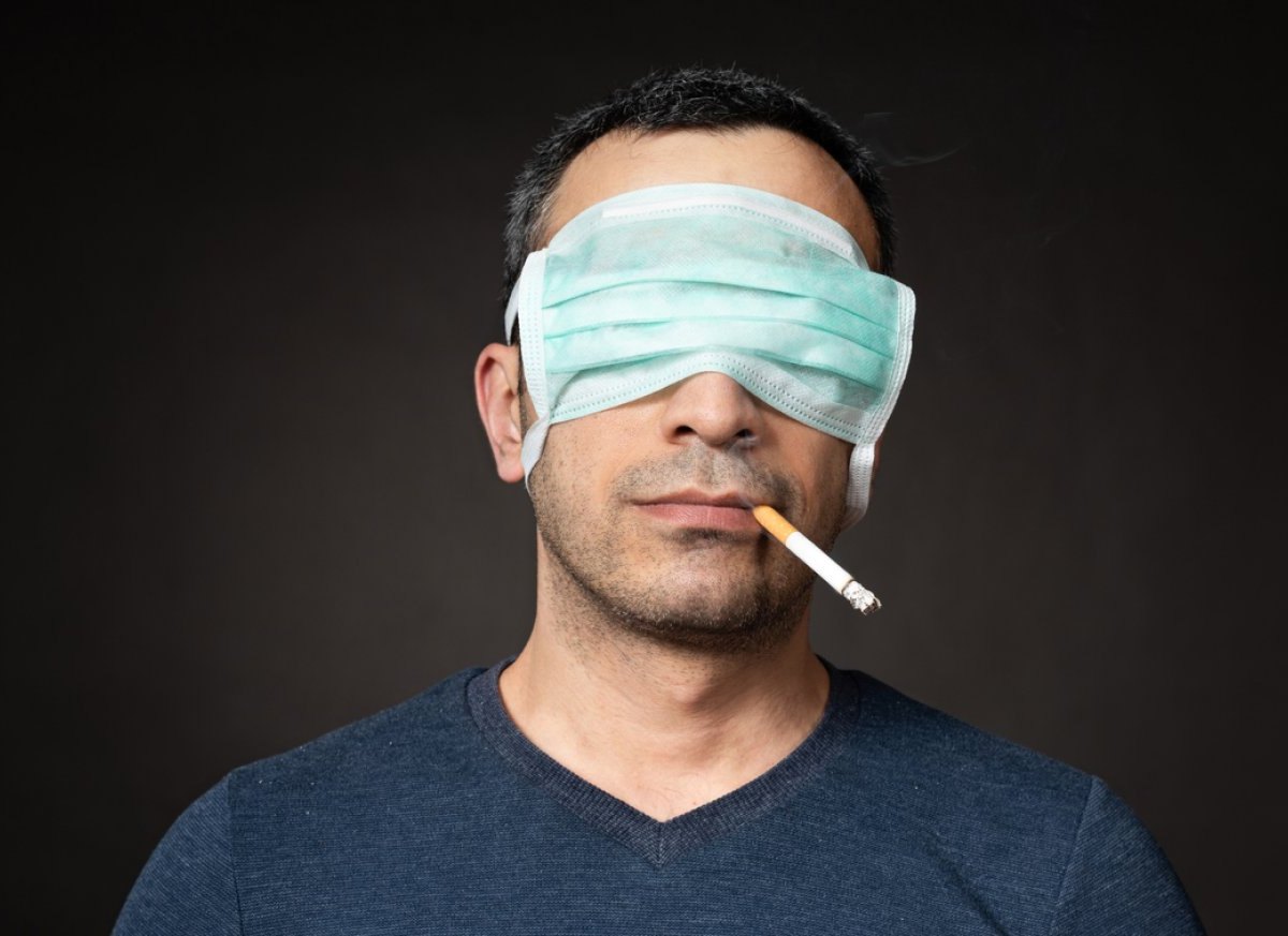Mann mit Zigarette im Mund und Maske auf den Augen