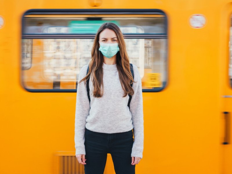 Frau mit Maske vor der U-Bahn