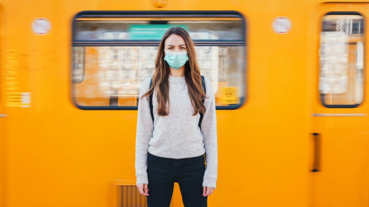 Frau mit Maske vor der U-Bahn