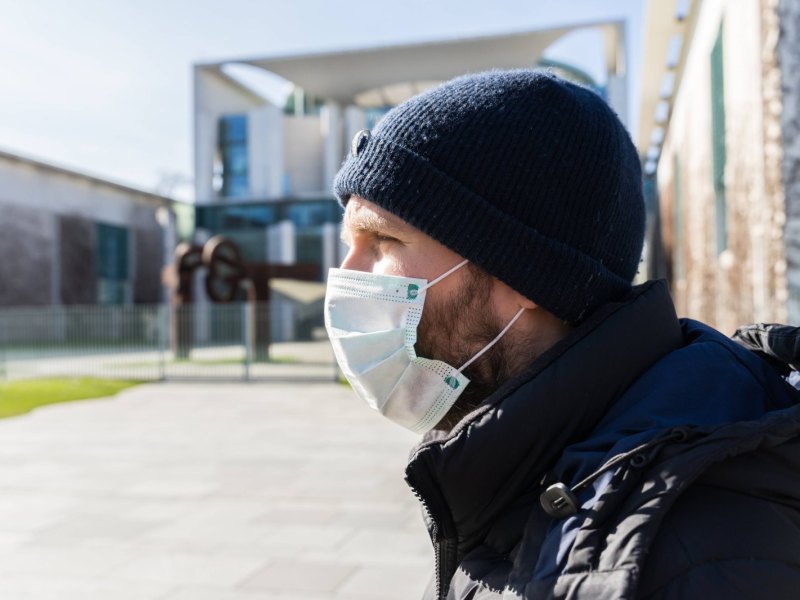Mann mit Mundschutz vor dem Bundeskanzleramt in Berlin.
