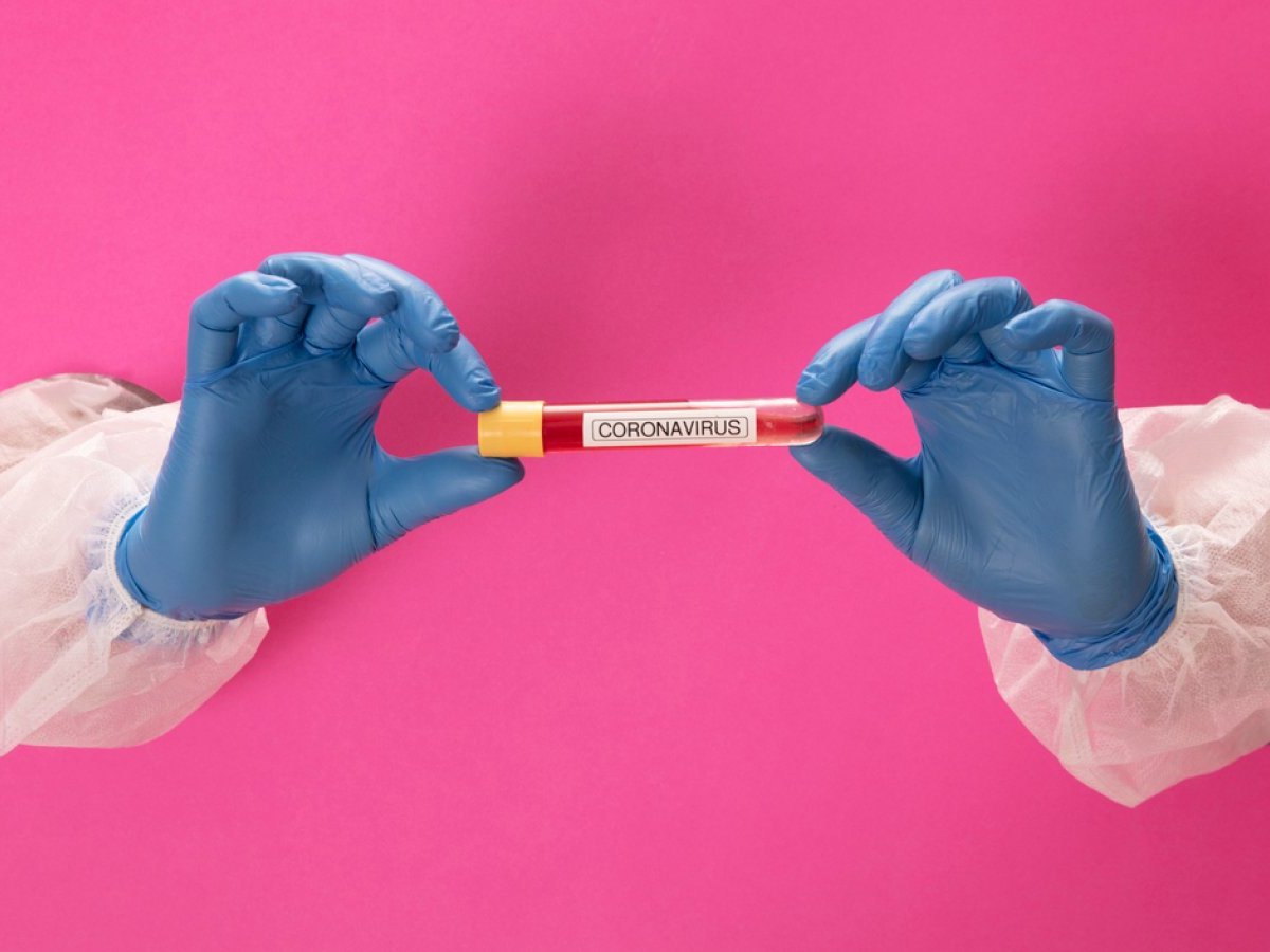 Zwei Hände halten ein Röhrchen mit der Aufschrift "Coronavirus".