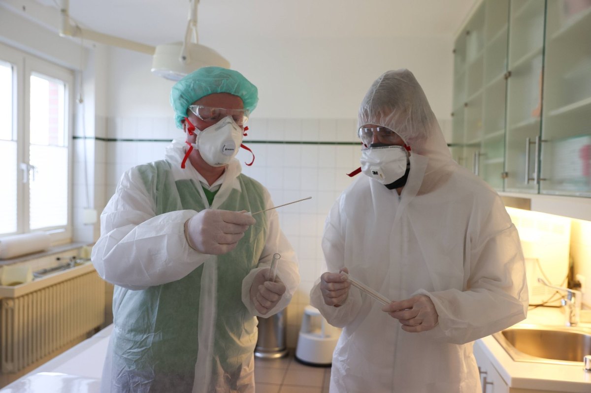 Zwei Menschen mit Schutzkleidung und Mundschutz im Labor.