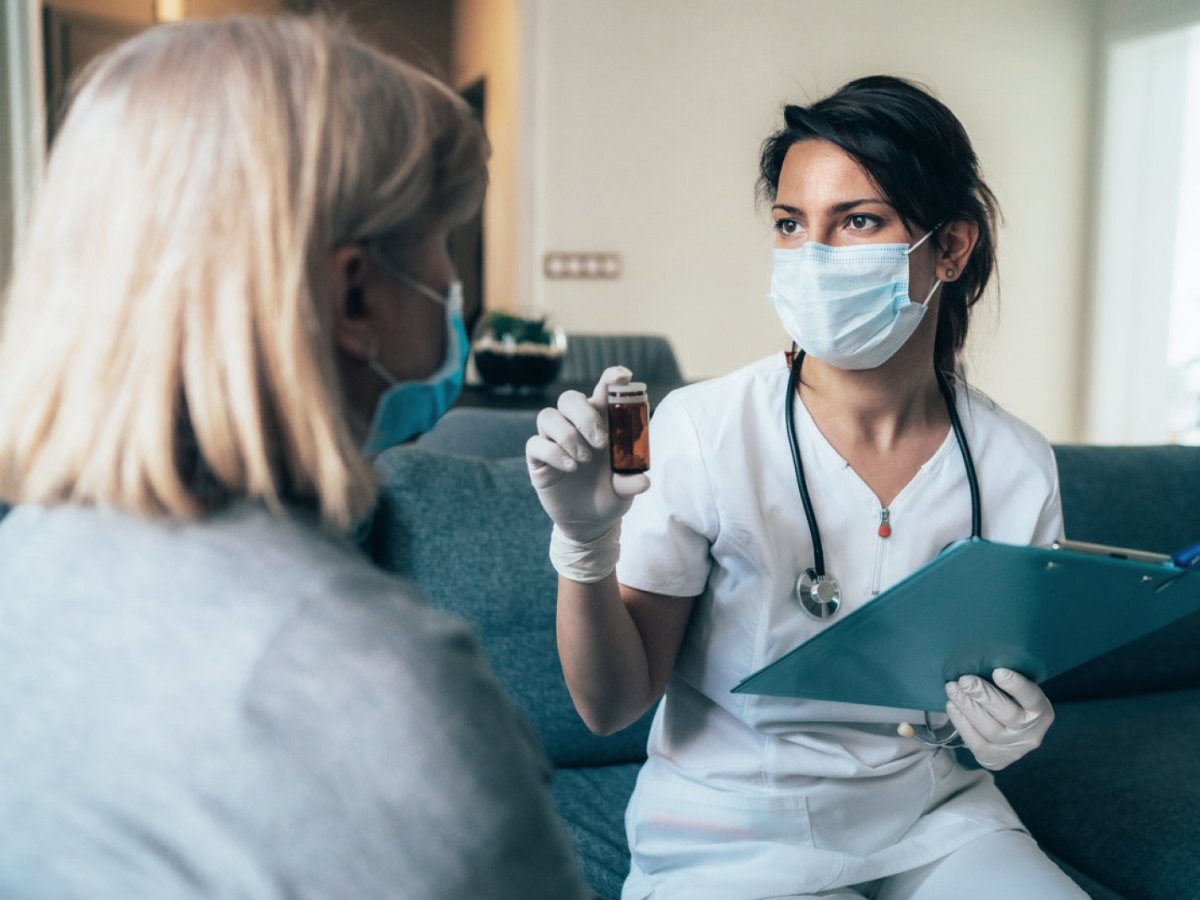 Medizinerin mit Mundschuzt bei einer Patientin.
