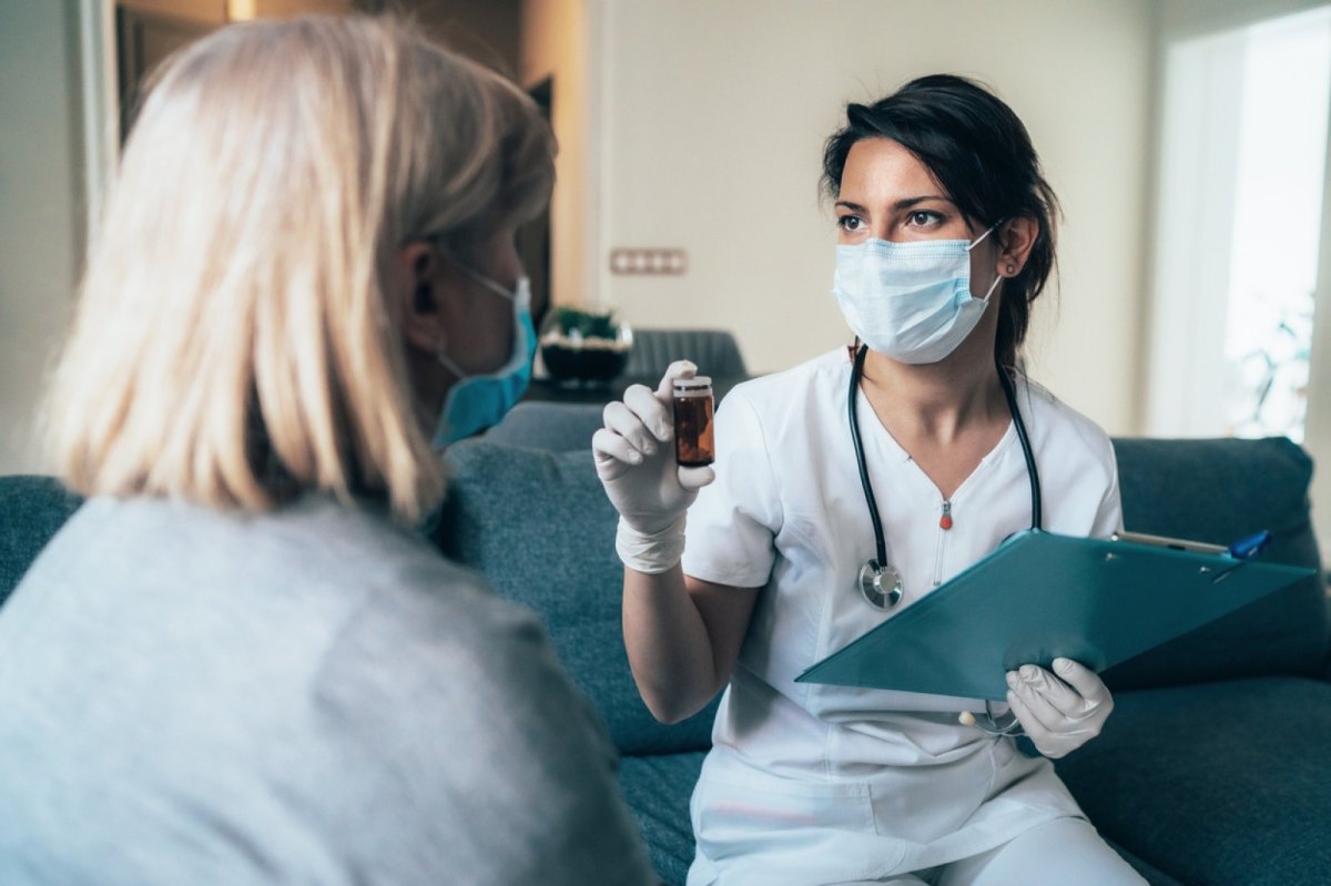 Medizinerin mit Mundschuzt bei einer Patientin.