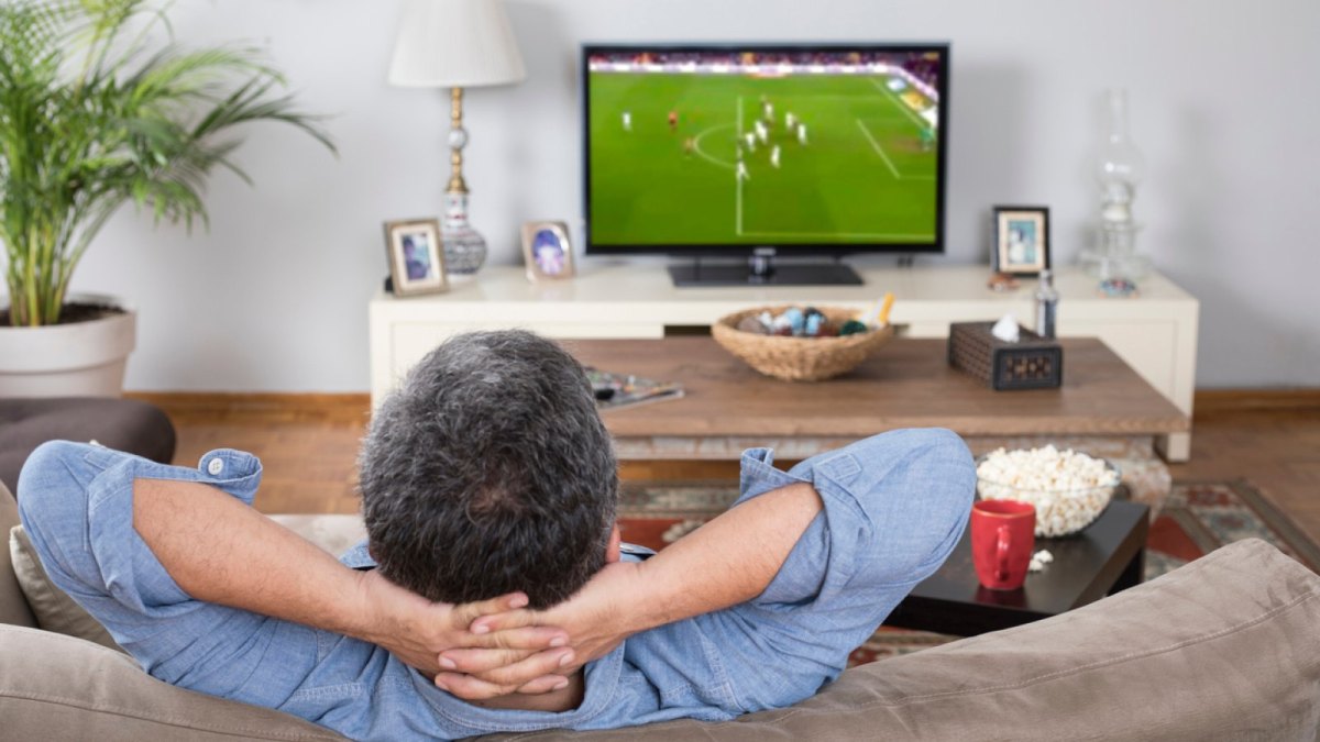 Mann sitzt vor dem TV und schaut Fußball.
