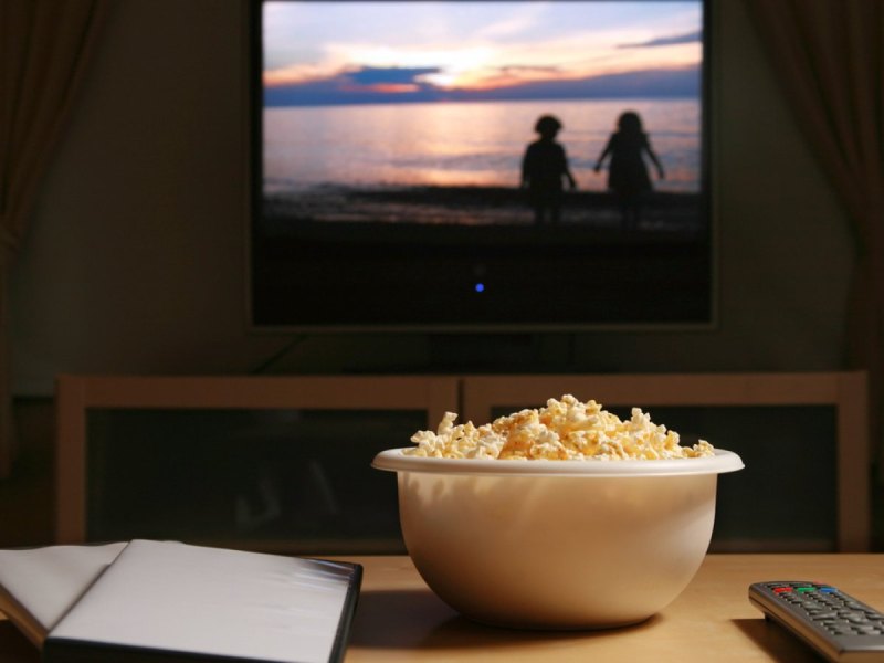 DVD-Hülle und Popcorn auf dem Couch-Tisch vor dem TV.