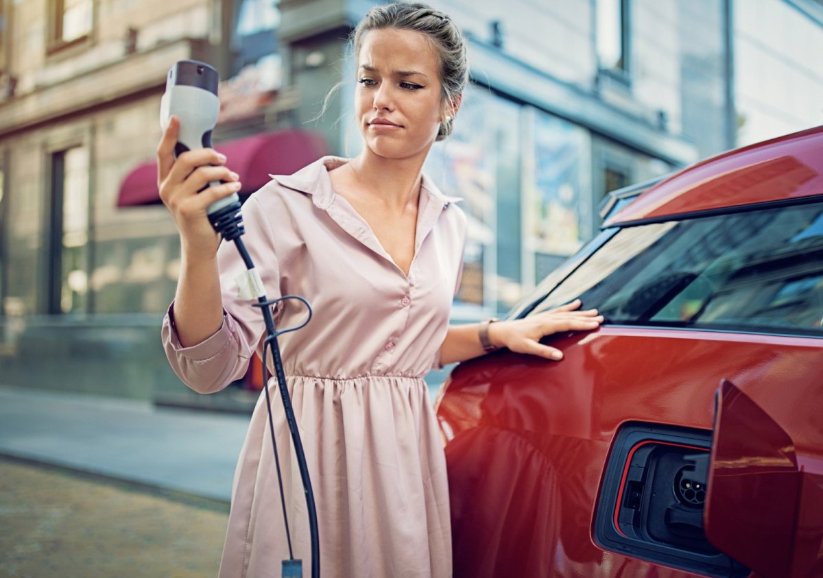 Frau beim Aufladen eines Elektroautos