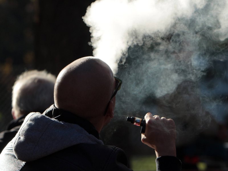Mann exhaliert Rauch aus E-Zigarette