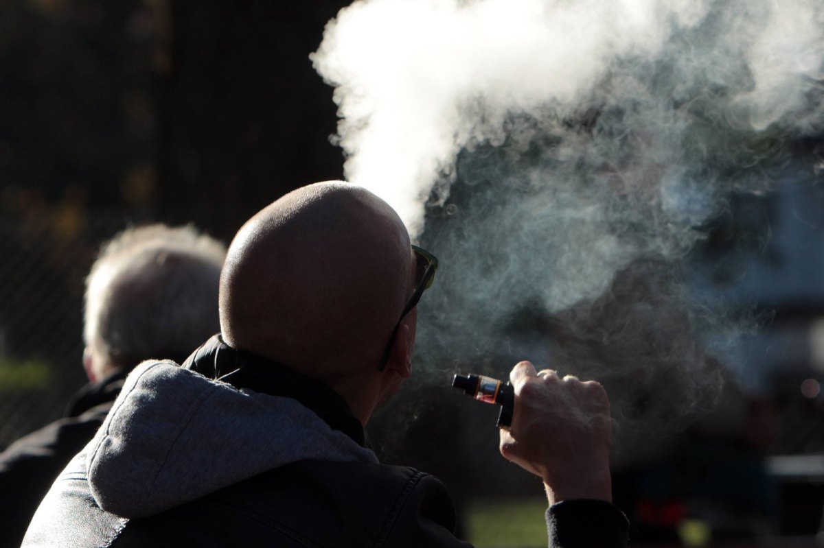 Mann exhaliert Rauch aus E-Zigarette