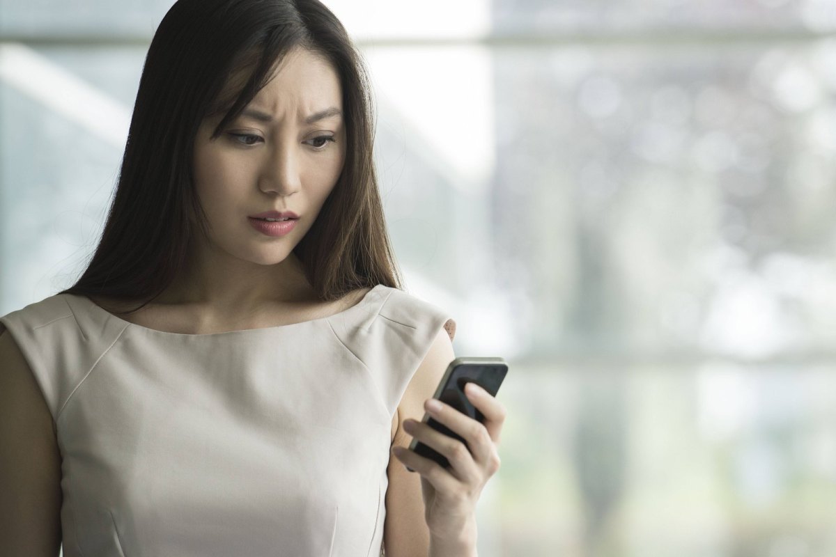 Frau schaut enttäuscht aufs Handy