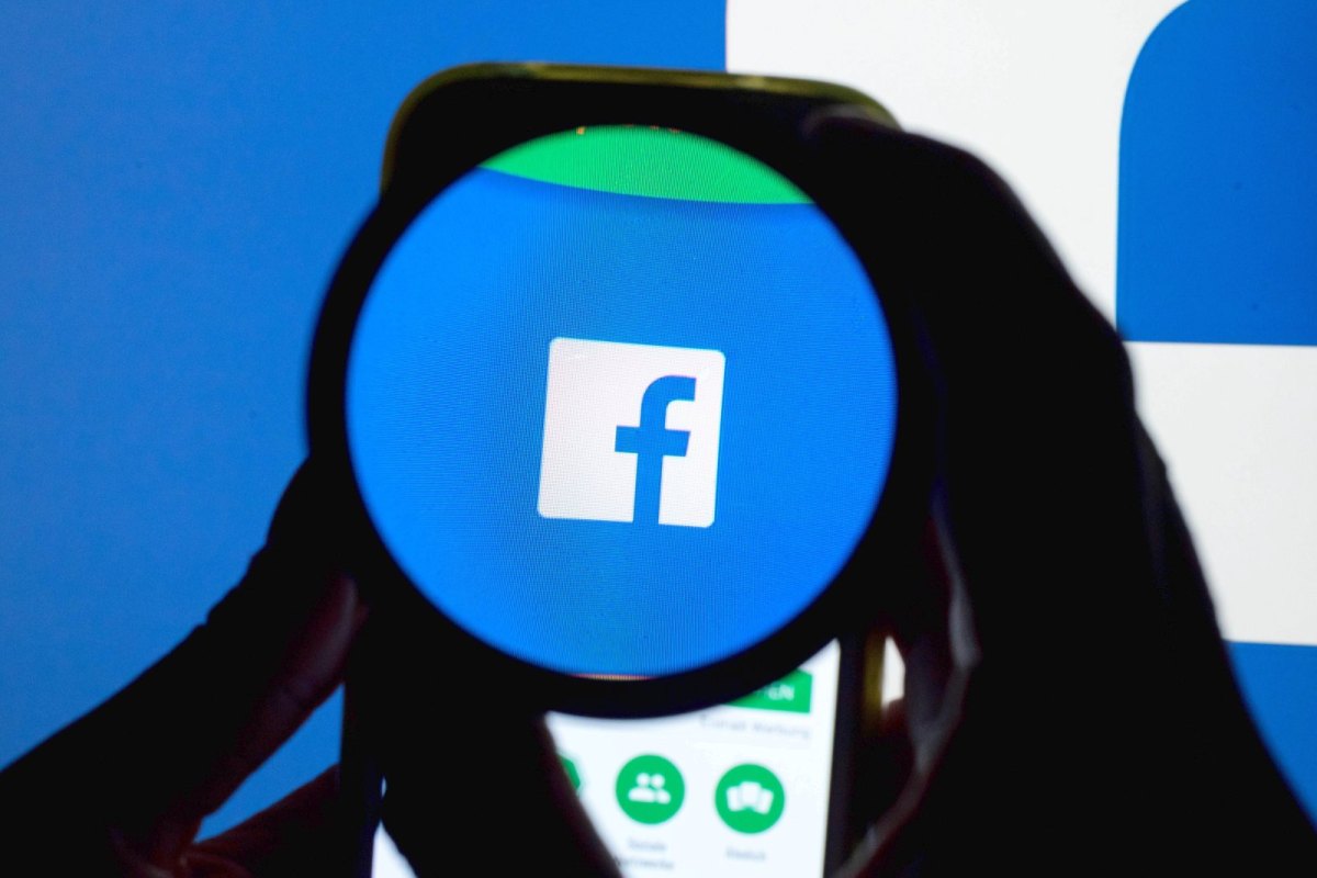 Das Icon der Social Media-Plattform Facebook ist auf einem Handy durch eine Linse zu sehen