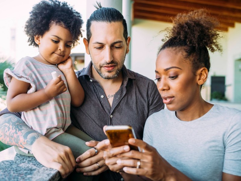 Dreiköpfige Familie mit Smartphone