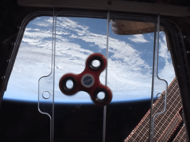 Fidget Spinner dreht sich im All mit der Erde im Hintergrund