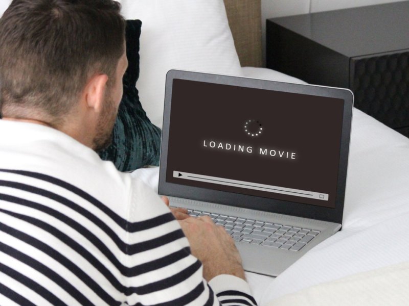 Mann lädt einen Film auf seinen Laptop.