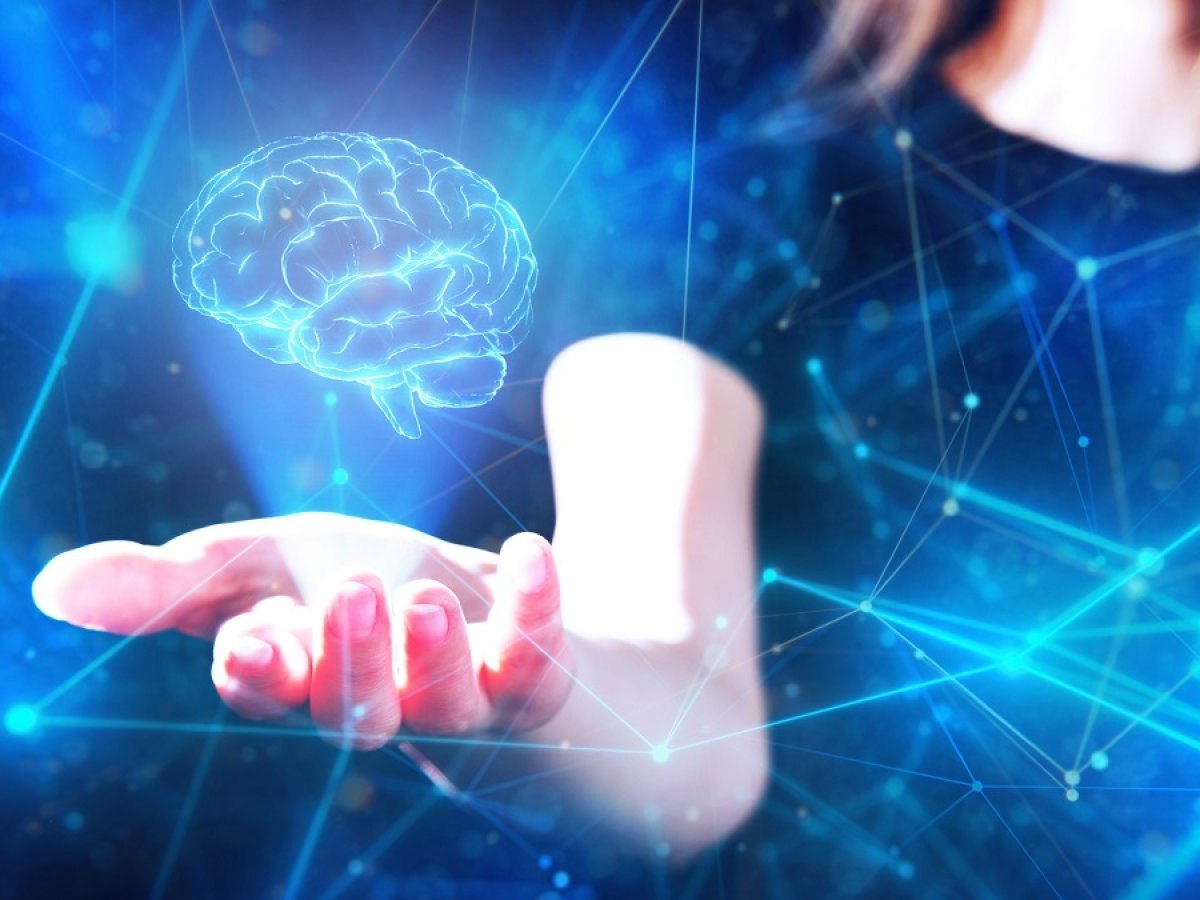 Gehirn-Hologram schwebt über der Hand einer Frau.