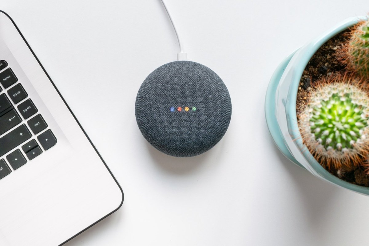 Google Assistant-Lautsprecher neben MacBook und Kaktus