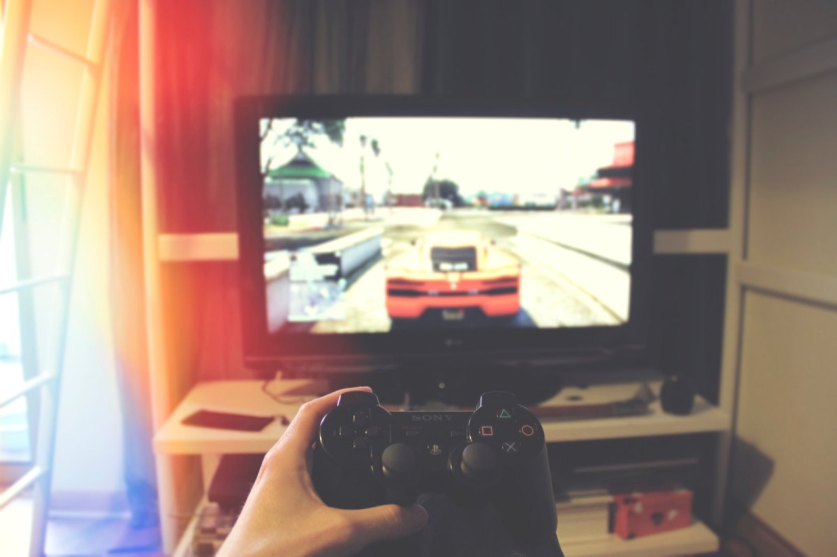 Hand mit Controller vor Bildschirm mit GTA 5