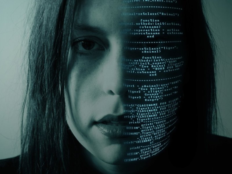 Gesicht einer Frau mit Programmiercode auf der eine Gesichtshälfte