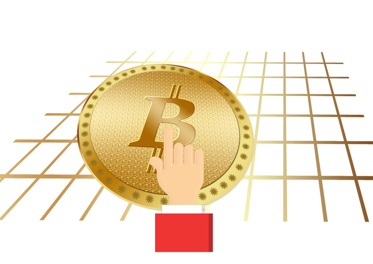 Eine Hand greift nach einer Bitcoin-Münze.