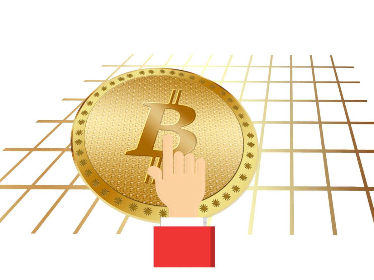 Eine Hand greift nach einer Bitcoin-Münze.