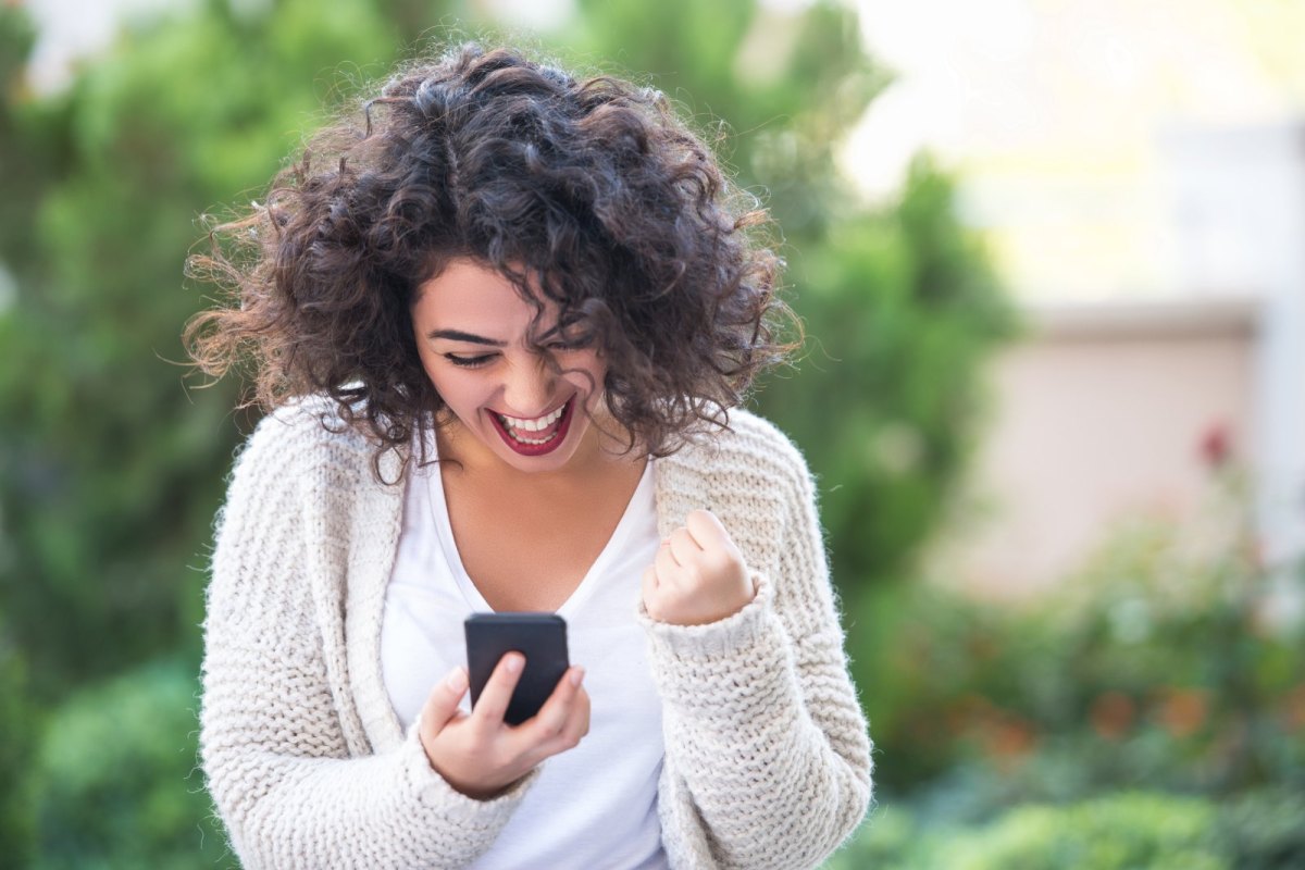 Frau freut sich über ihrem Handy.