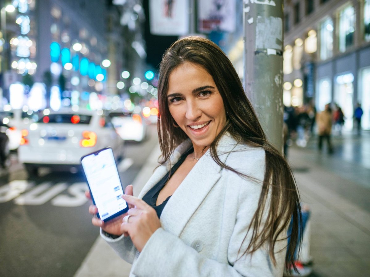 Frau zeigt auf smartphone und lächelt