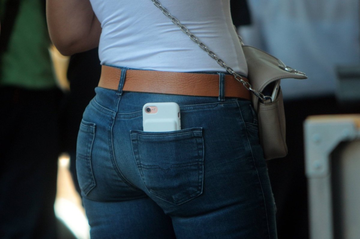 Eine Frau trägt ihr Handy in der Hosentasche.