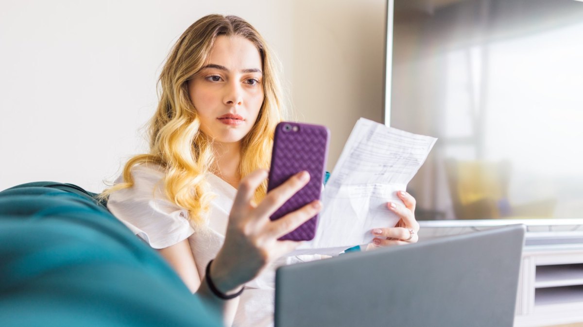 Frau mit Rechnung und Handy in der Hand