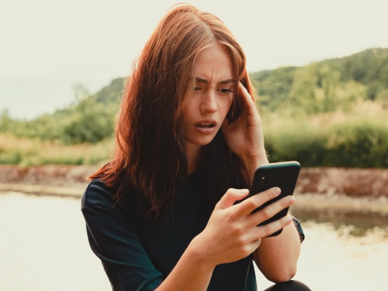 Frau erschrocken am Handy