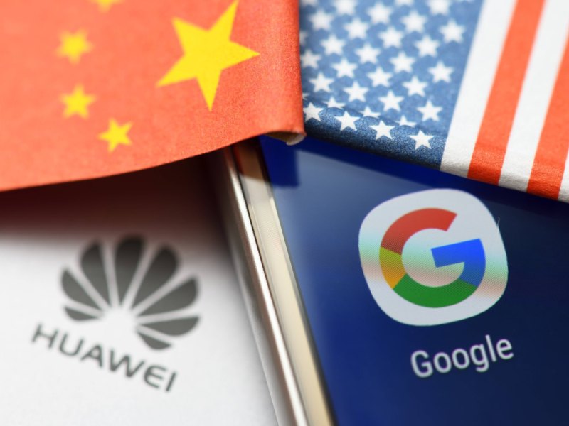 Huawei Handy liegt neben Google Handy mit China und US-Flagge