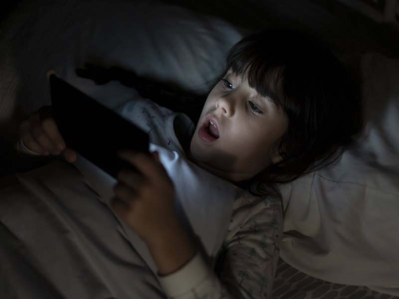 Mädchen im Bett mit einem Smartphone in der Hand