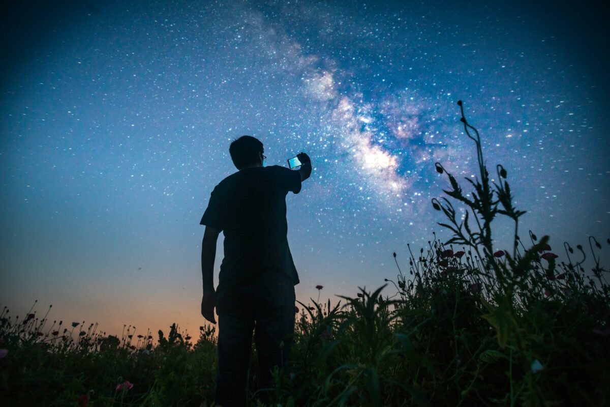 Mann mit Handy fotografiert den Sternenhimmel